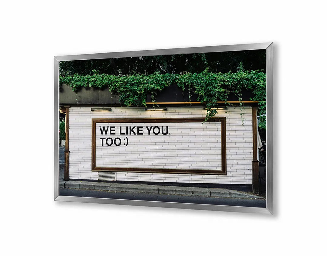 Metalen Magneetbord met We Like You Too tekst op een ruwe bakstenen muur