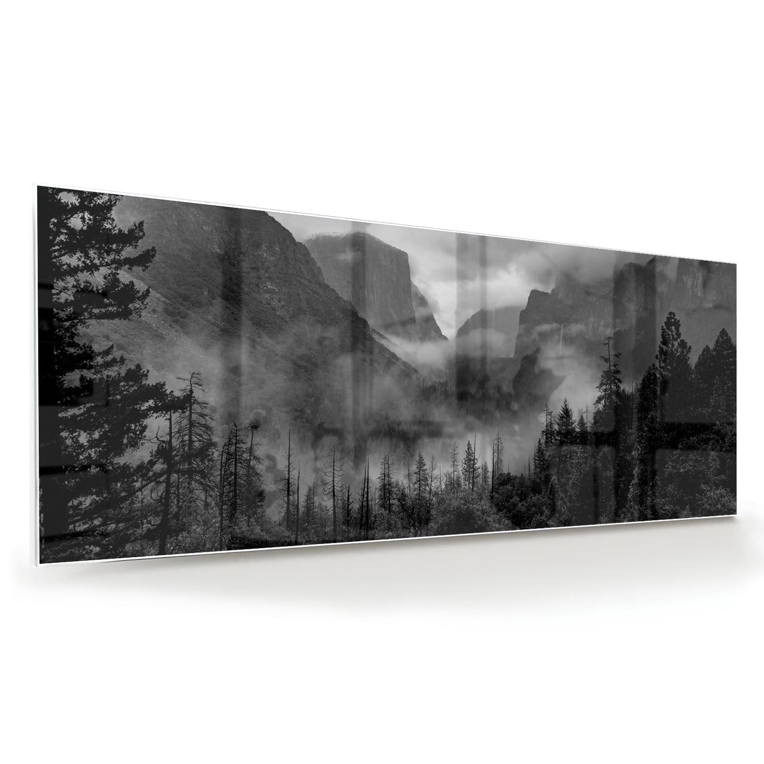 Zwart-wit glazen schilderij van een sereen berglandschap aan de muur.