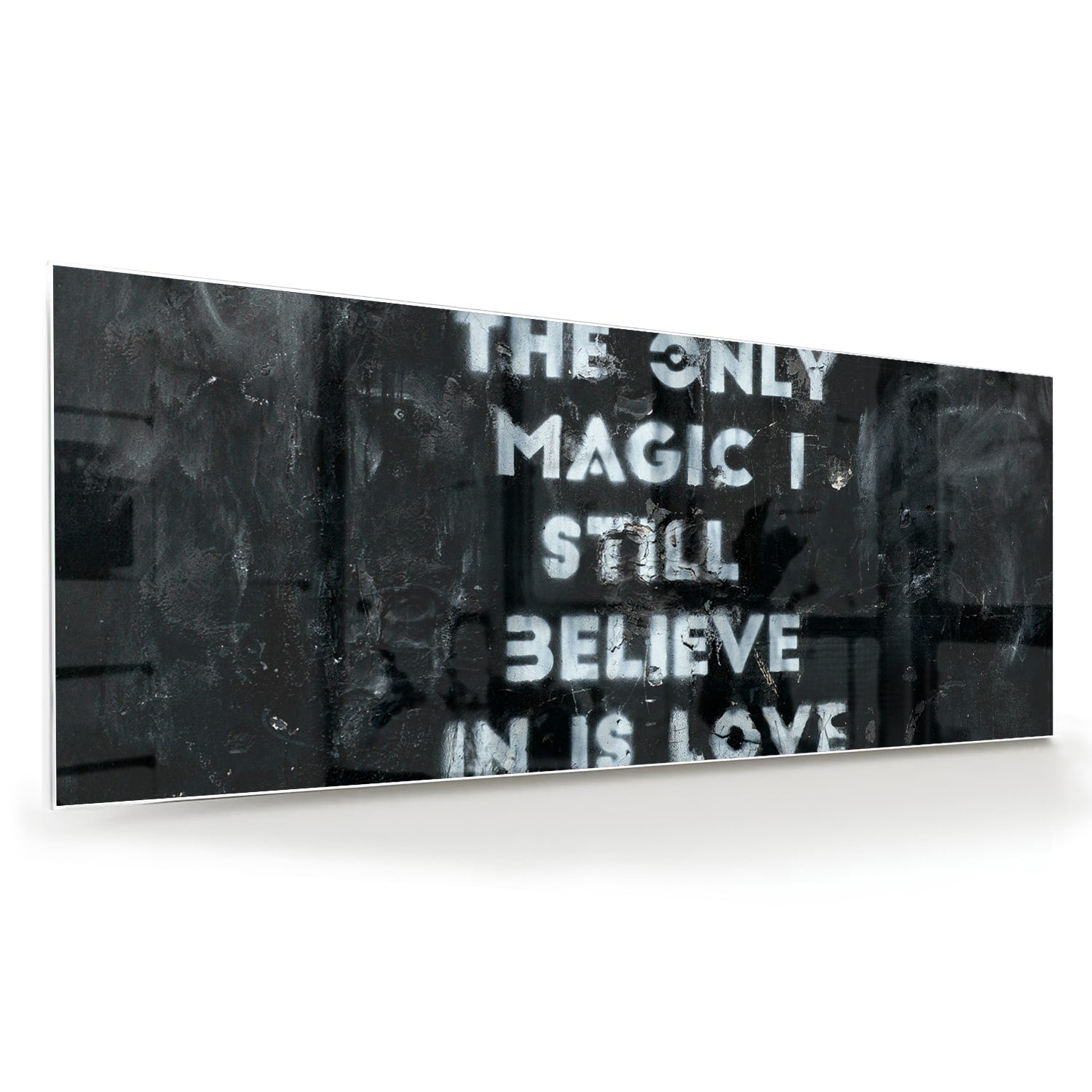 Glazen schilderij met de tekst 'The only magic I still believe in is love', hangt aan de muur in een lichte woonkamer.
