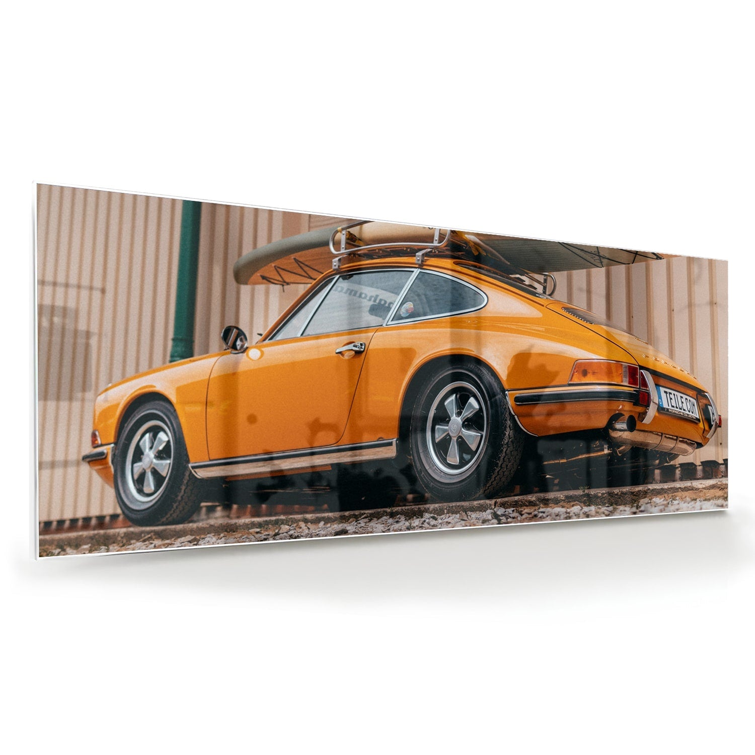 Een glazen schilderij van een oranje auto met een surfbord op het dak, gepresenteerd in een moderne woonkamer.