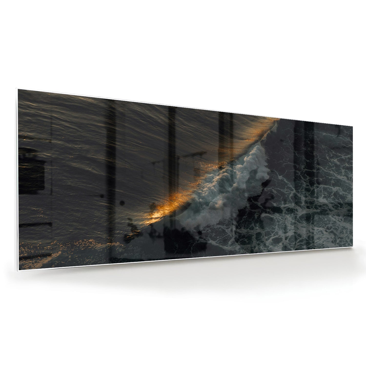 Zwart glazen schilderij van een zeegezicht met gouden accenten, hangt aan een lichtgekleurde muur.