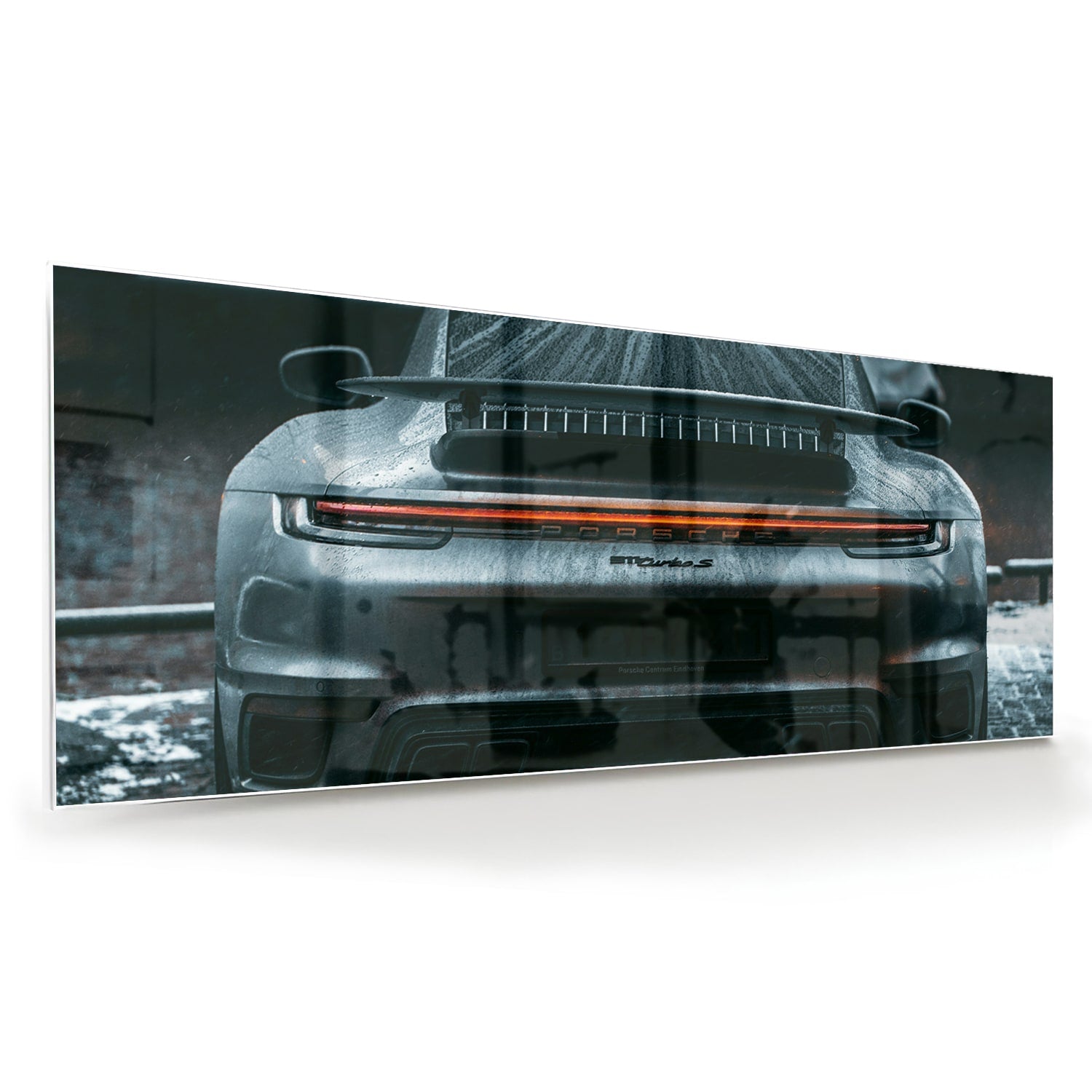 Glazen schilderij van een sportwagen aan de muur in een lichte woonkamer.