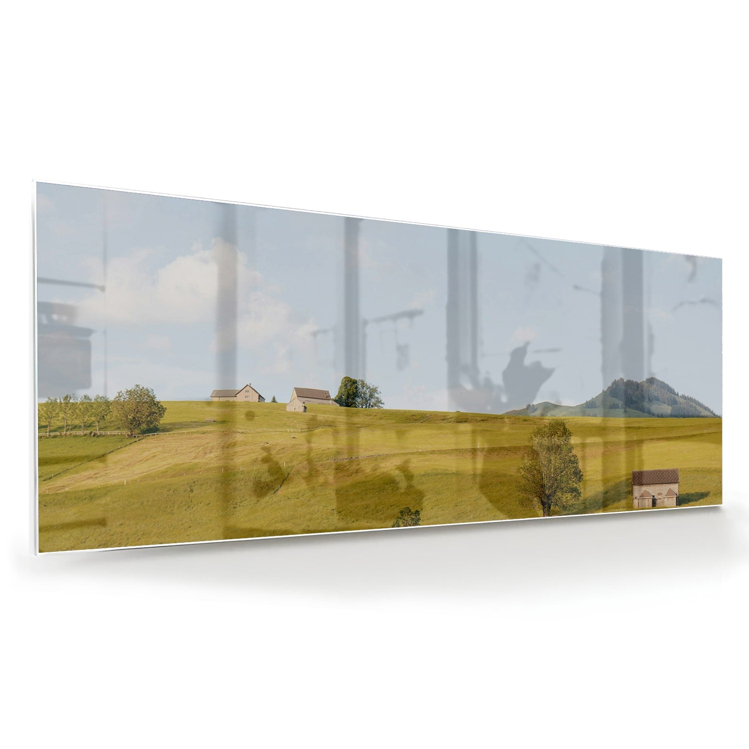 Glazen schilderij met groene heuvels en boerderijen op een witte muur.