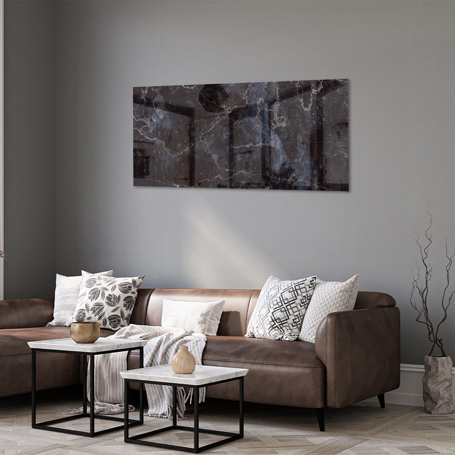 Glazen schilderij met donker marmerlook aan een lichte muur in een moderne woonkamer.