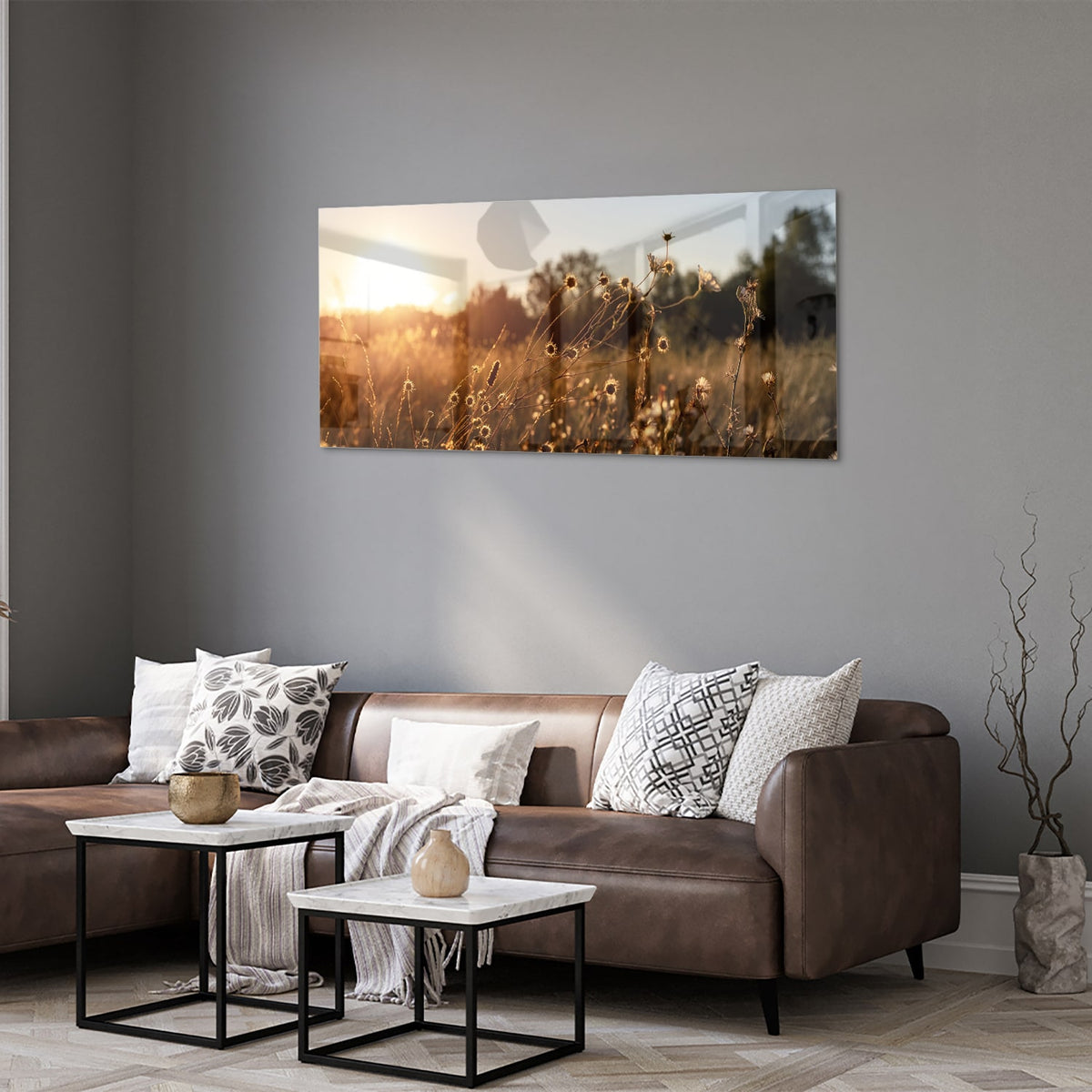 Glazen schilderij van een zonsondergang met bloeiende bloemen, hangend aan een witte muur.