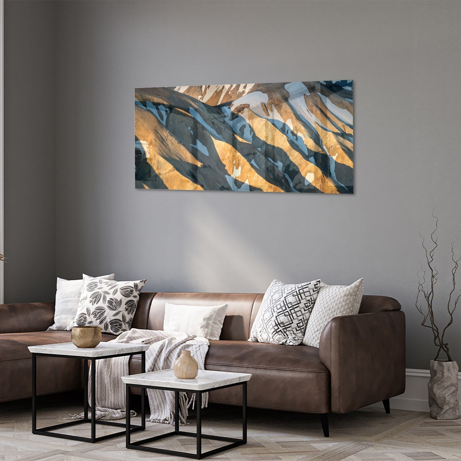 Glazen schilderij van bergen in blauw en goud, hanging in een stijlvolle kamer.