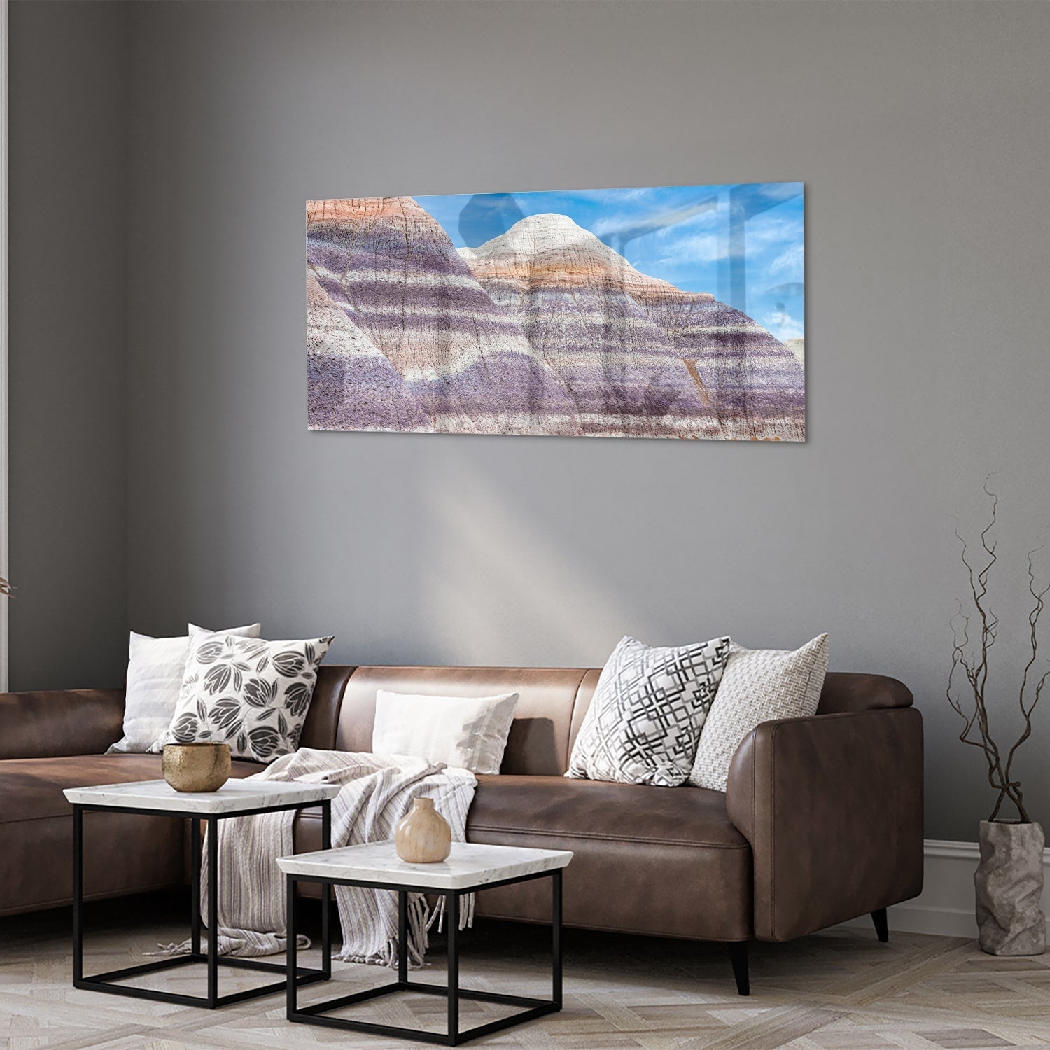 Glazen schilderij van bergen met een blauwe lucht in een moderne woonkamer.