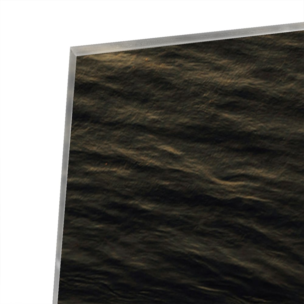 Zwart glazen schilderij van een zeegezicht met gouden accenten, hangt aan een lichtgekleurde muur.