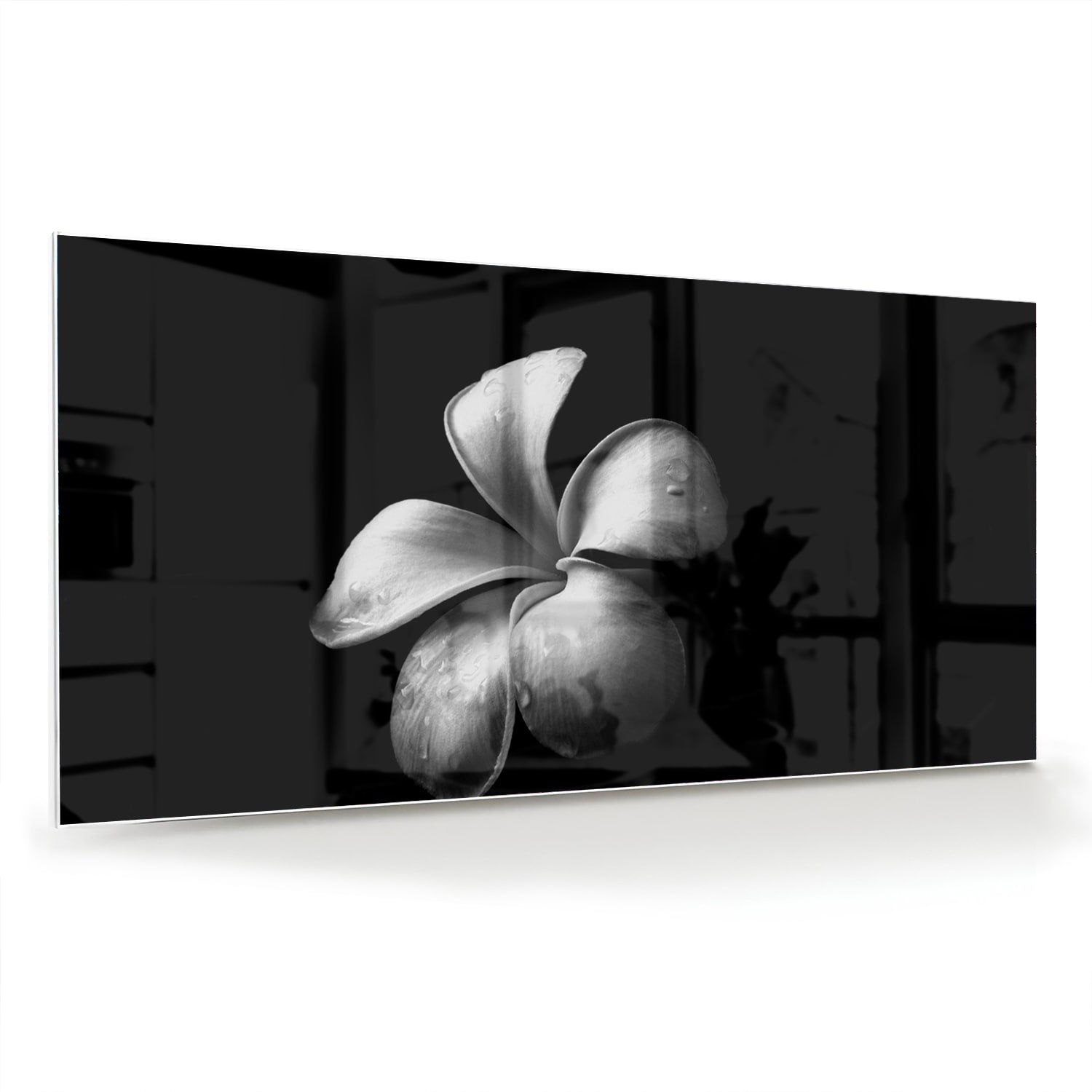Zwart glazen schilderij met bloemmotief boven een houten kast in een lichte kamer.