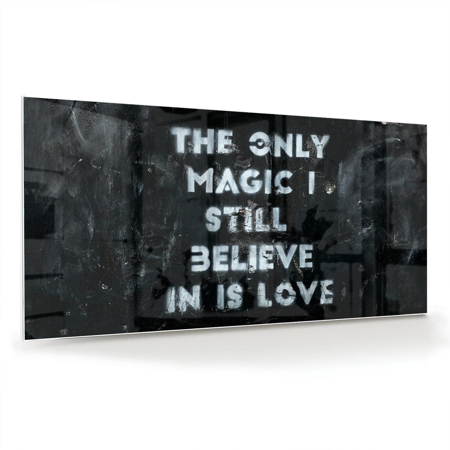 Glazen schilderij met de tekst 'The only magic I still believe in is love', hangt aan de muur in een lichte woonkamer.