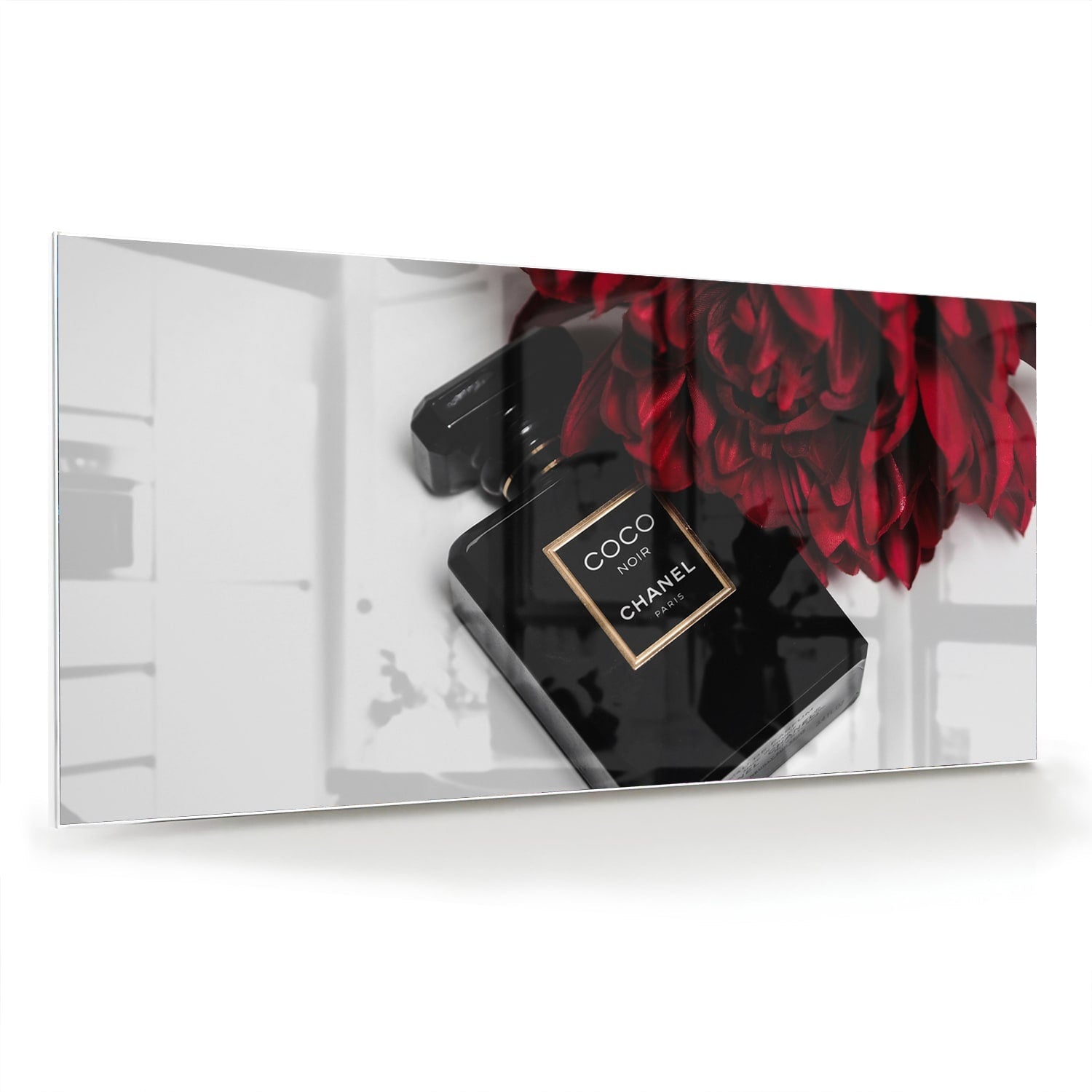 Glazen schilderij van parfumfles met rode bloemen op een witte muur
