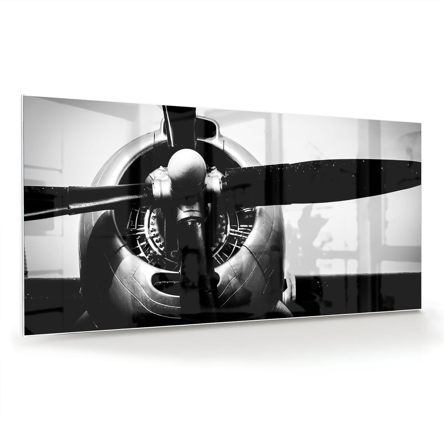 Zwart-wit glazen schilderij van een vintage vliegtuigpropeller tegen een lichte muur.