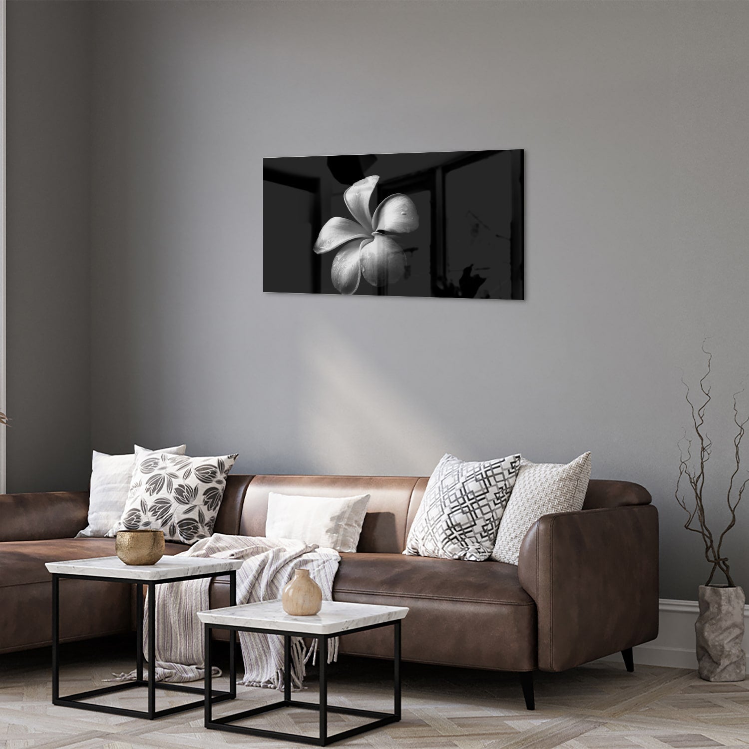 Zwart glazen schilderij met bloemmotief boven een houten kast in een lichte kamer.