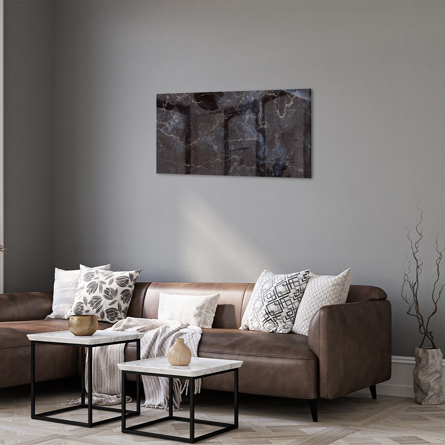 Glazen schilderij met donker marmerlook aan een lichte muur in een moderne woonkamer.