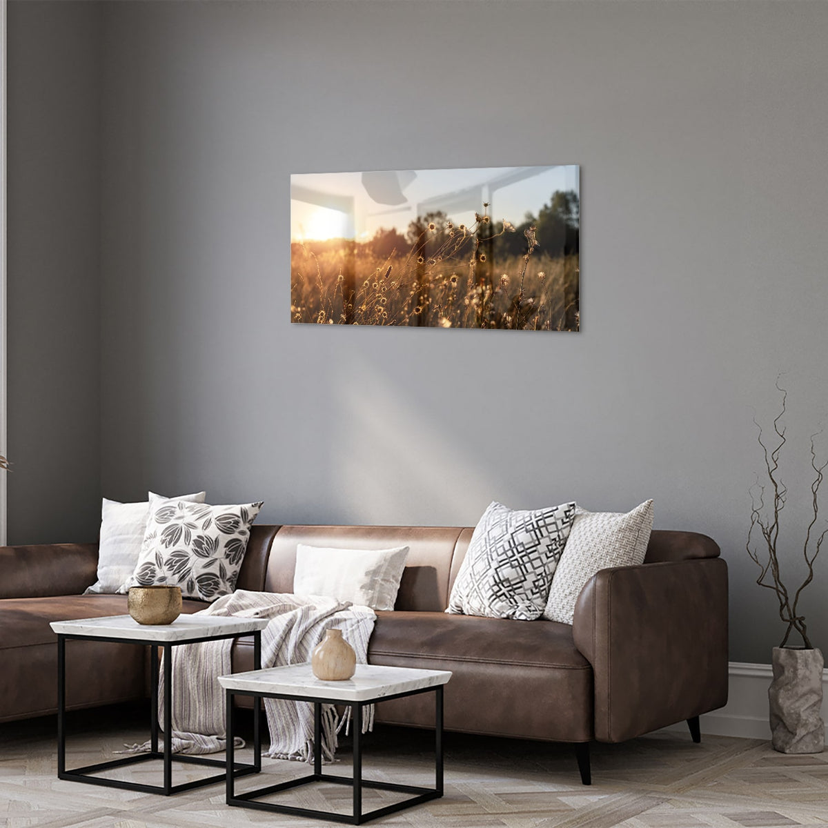 Glazen schilderij van een zonsondergang met bloeiende bloemen, hangend aan een witte muur.