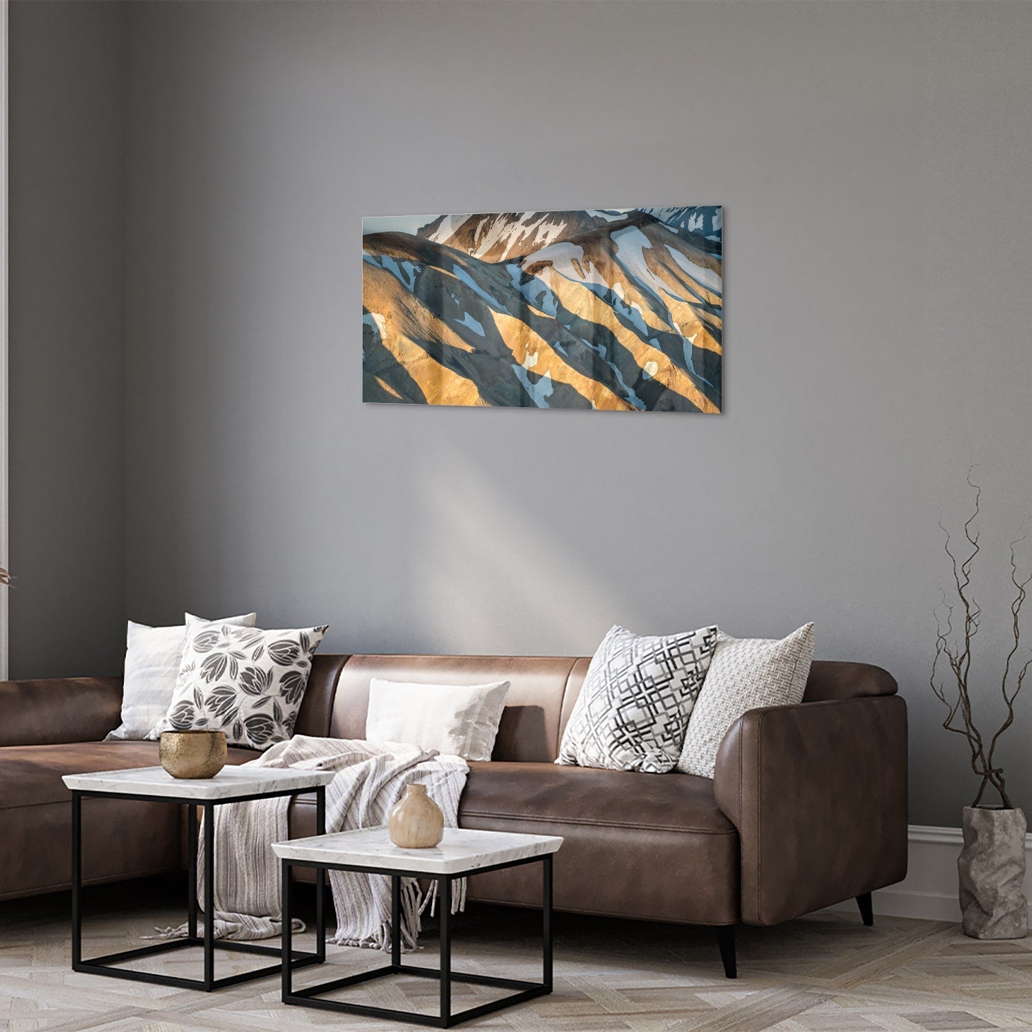Glazen schilderij van bergen in blauw en goud, hanging in een stijlvolle kamer.