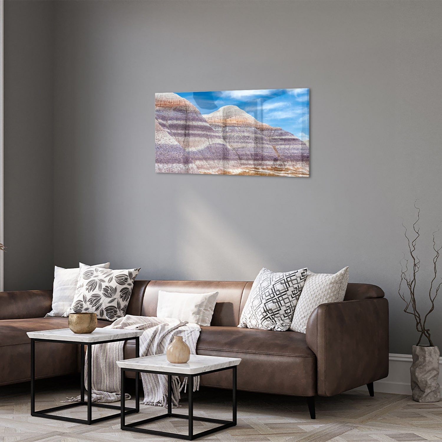 Glazen schilderij van bergen met een blauwe lucht in een moderne woonkamer.