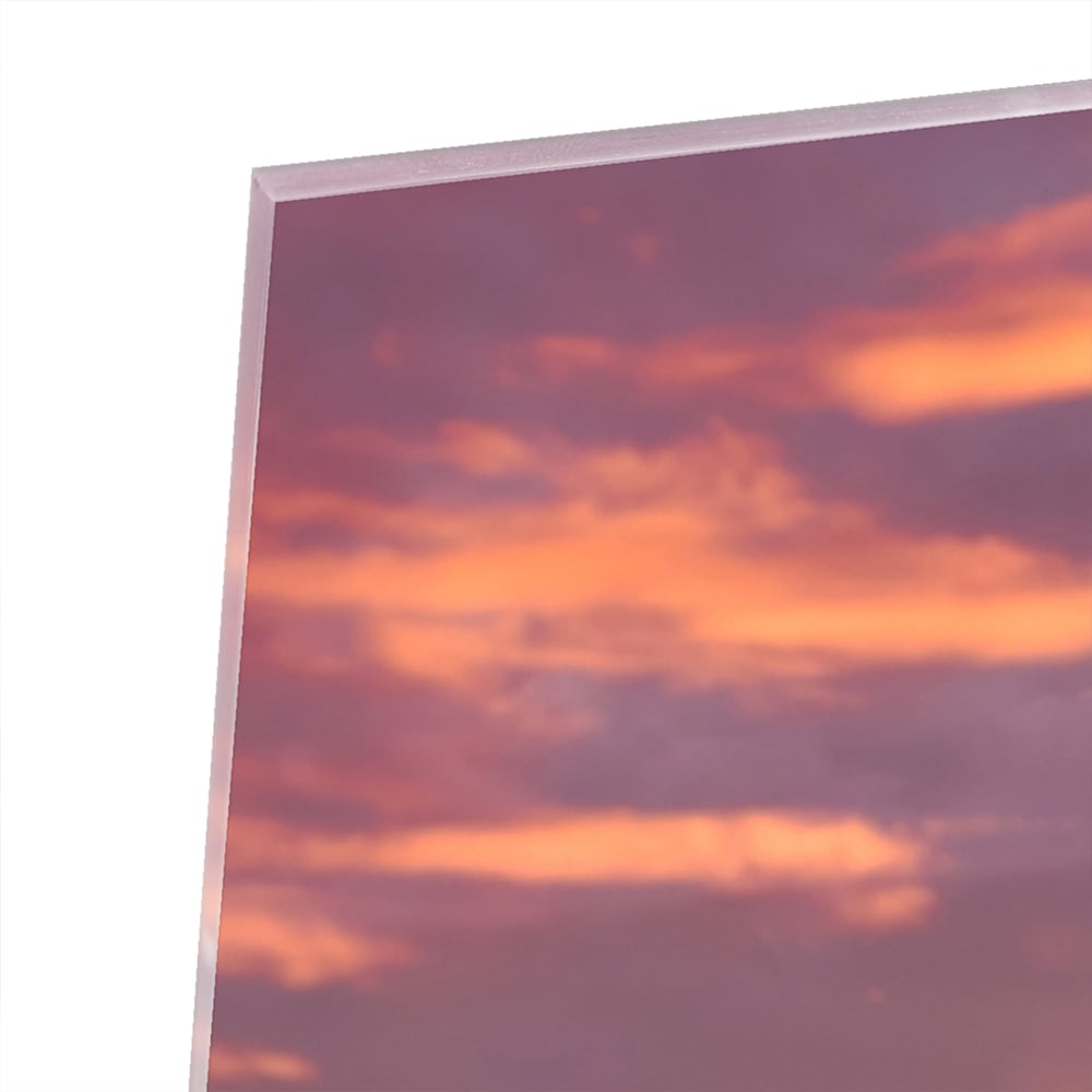 Glazen schilderij van een stadspanorama bij zonsondergang met bergen op de achtergrond.