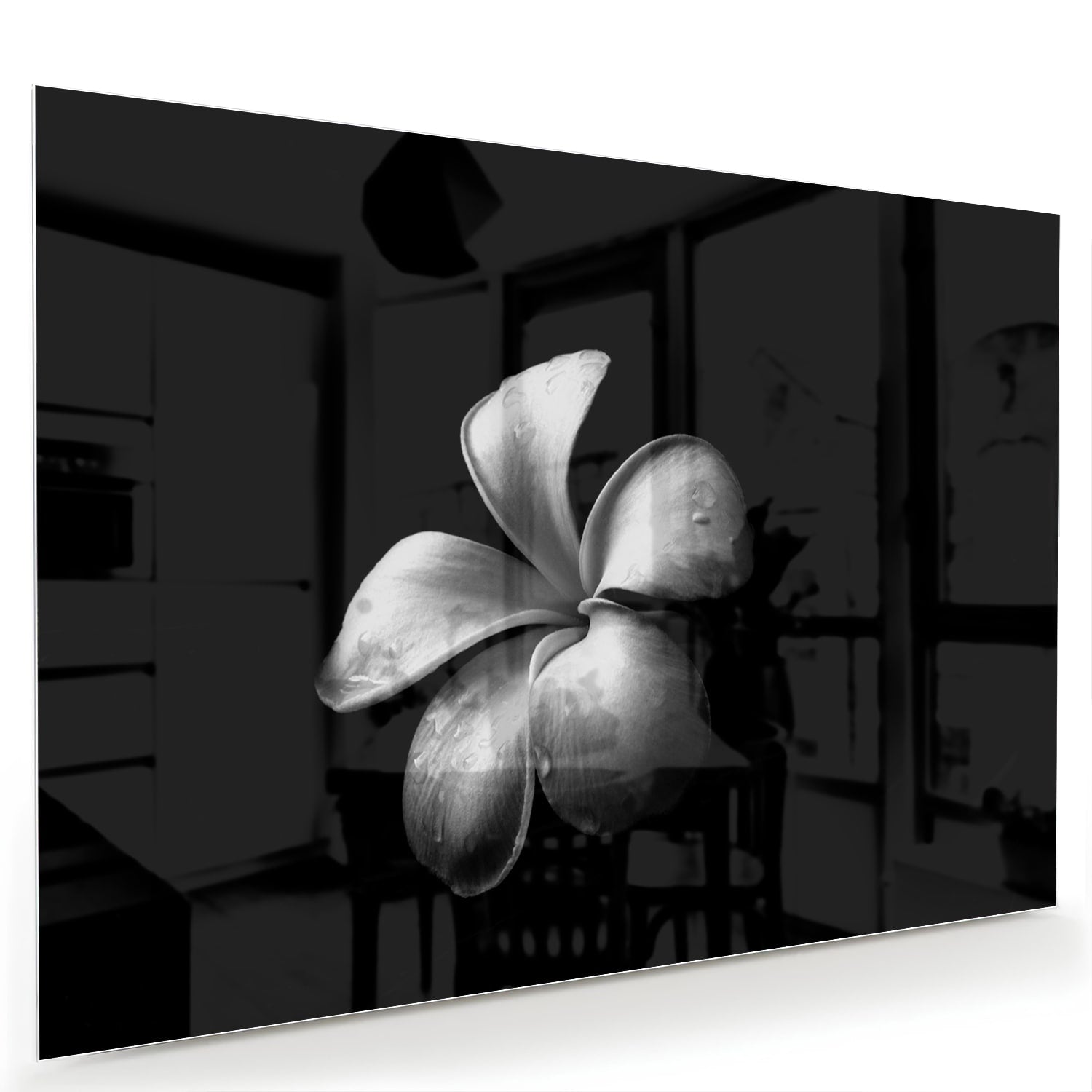 Zwart glazen schilderij met bloemmotief boven een houten kast in een lichte kamer.