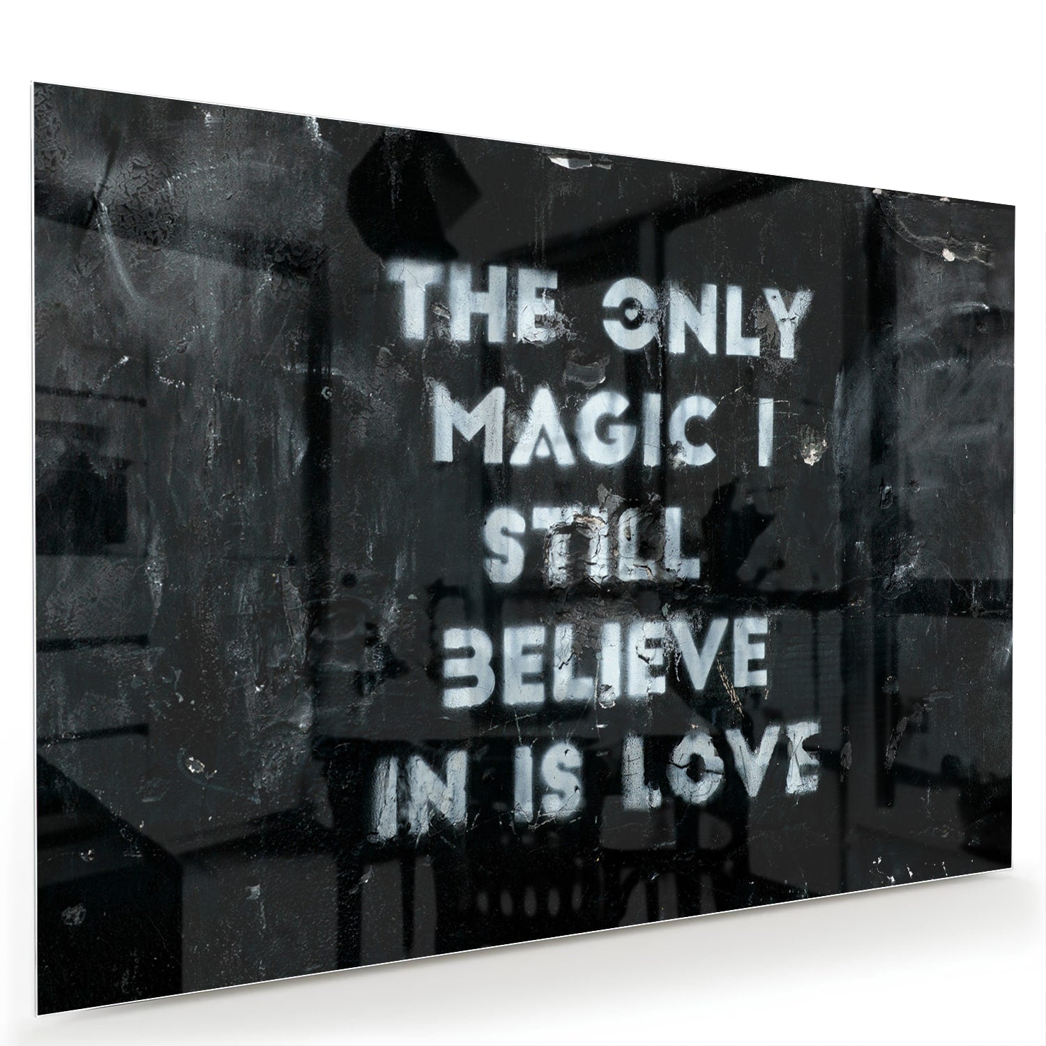 Glazen schilderij met de tekst 'The only magic I still believe in is love', hangt aan de muur in een lichte woonkamer.