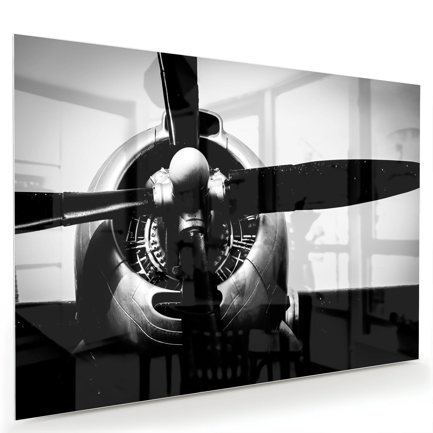 Zwart-wit glazen schilderij van een vintage vliegtuigpropeller tegen een lichte muur.