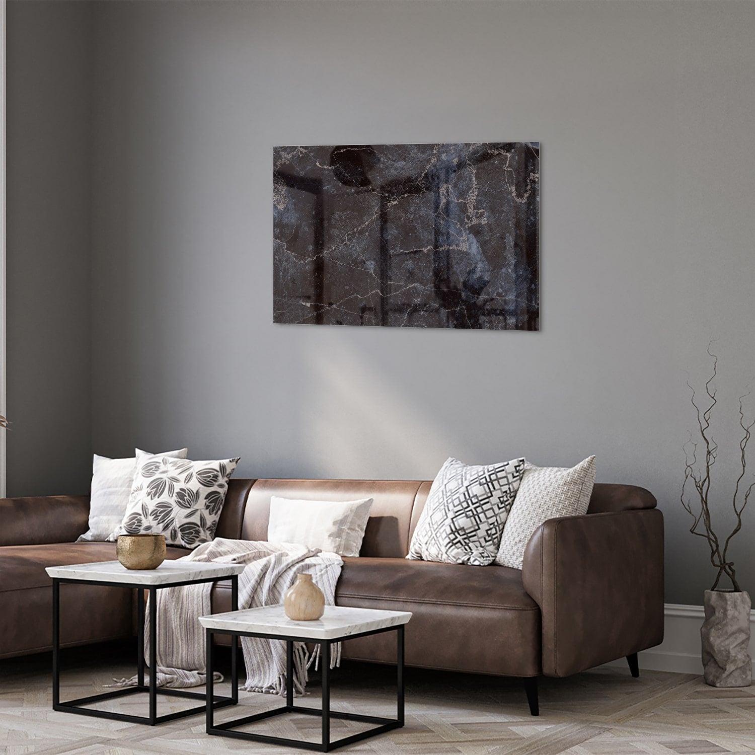 Glazen schilderij met donker marmerlook aan een lichte muur in een moderne woonkamer.