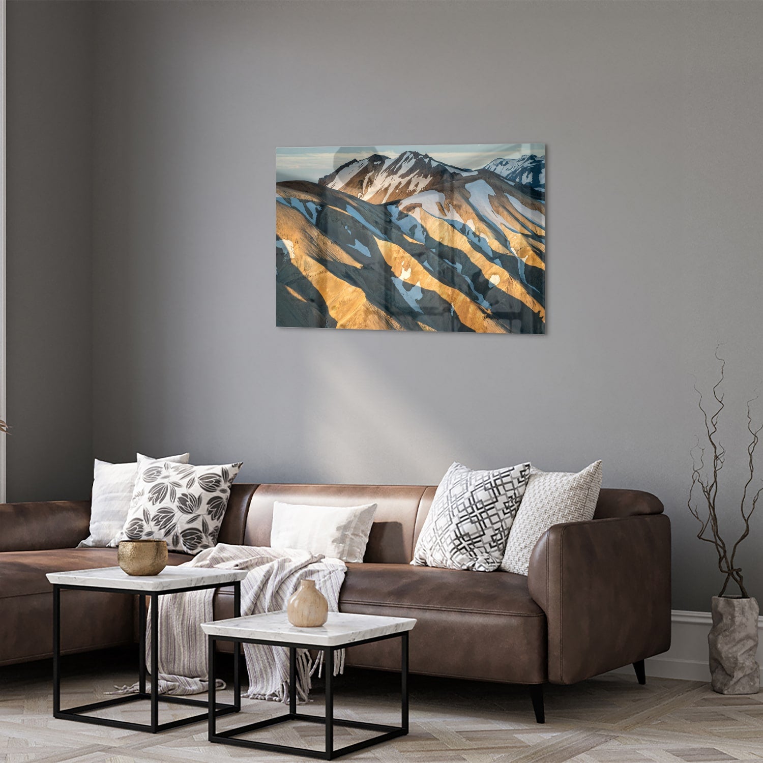 Glazen schilderij van bergen in blauw en goud, hanging in een stijlvolle kamer.