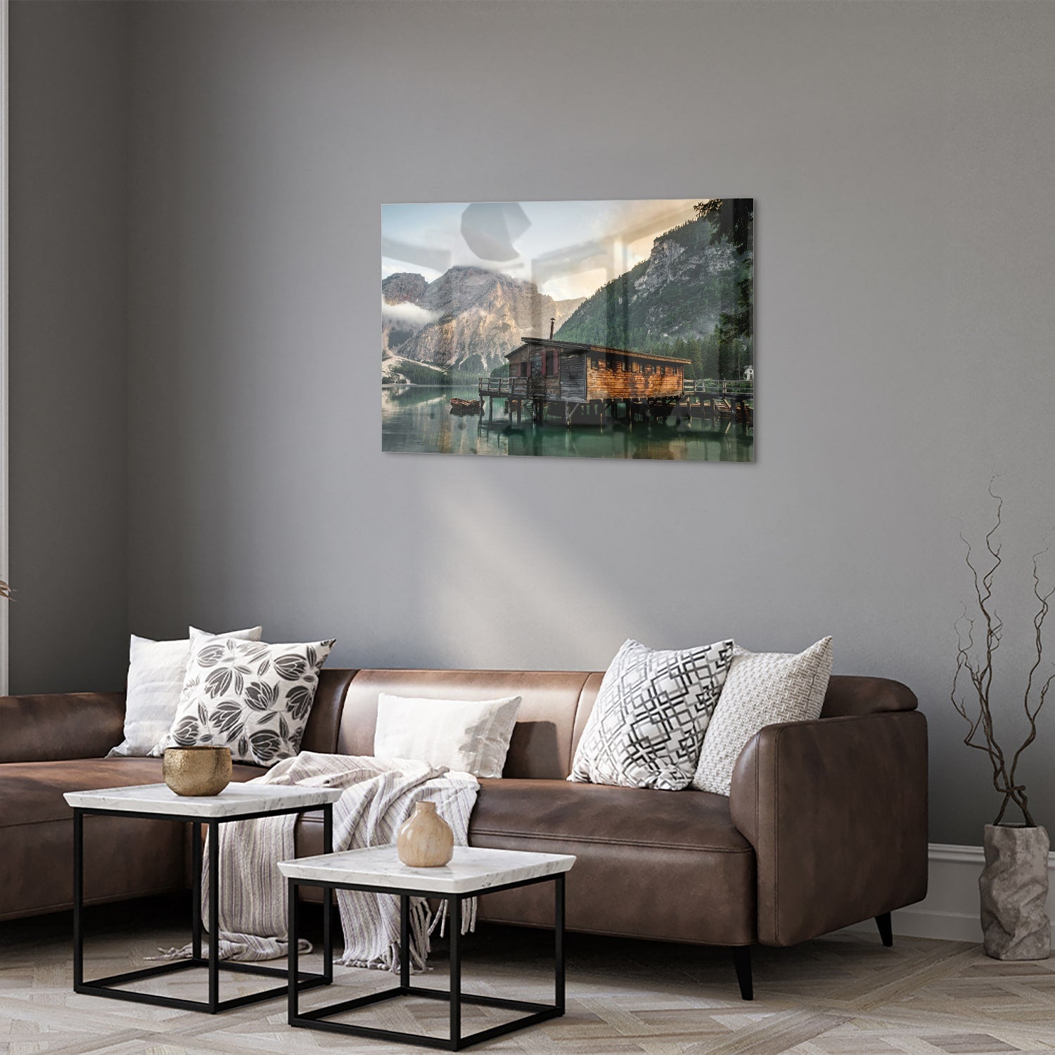 Glazen schilderij van een berghut aan een kalm meer met bergen op de achtergrond.