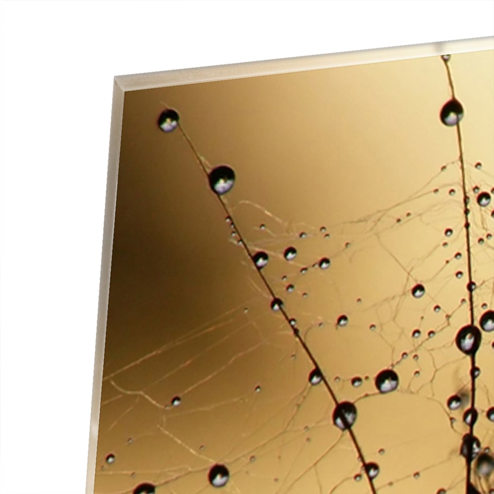 Glazen schilderij met gouden waterdruppels op een lichte muur.
