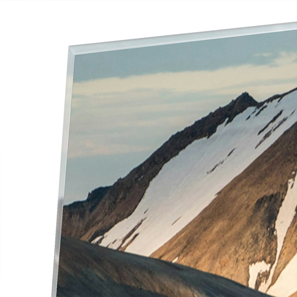Glazen schilderij van bergen in blauw en goud, hanging in een stijlvolle kamer.