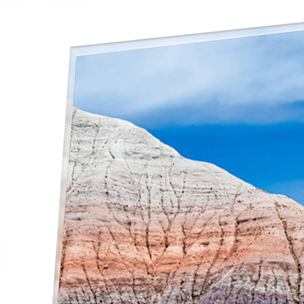 Glazen schilderij van bergen met een blauwe lucht in een moderne woonkamer.
