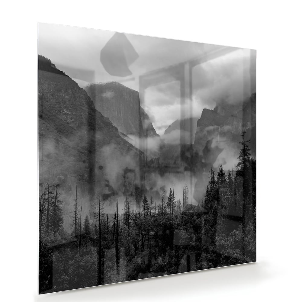 Zwart-wit glazen schilderij van een sereen berglandschap aan de muur.