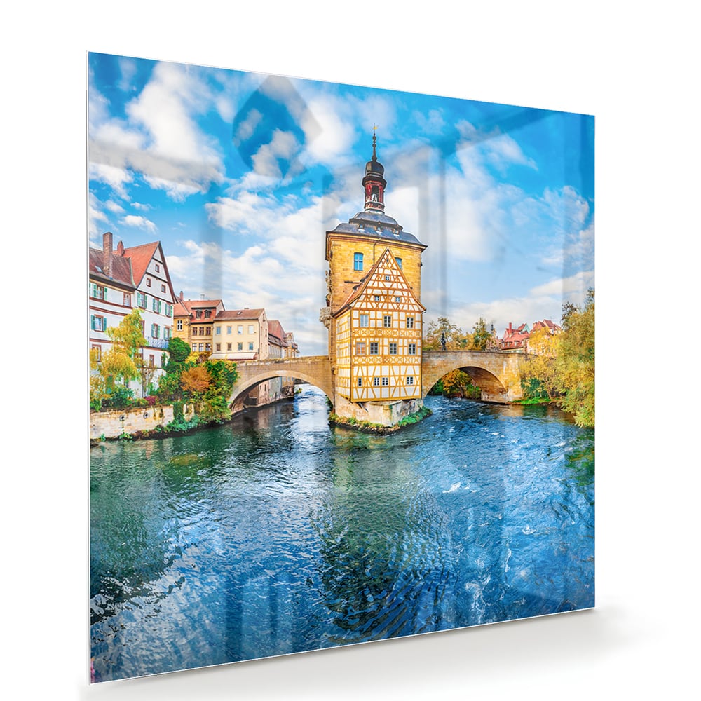 Glazen schilderij van een schilderachtig stadje aan het water met kleurrijke gebouwen en een helderblauwe lucht.