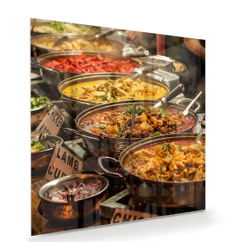 Glazen schilderij met een kleurrijke selectie van Indiaas eten, waaronder lamsvlees en groenten.