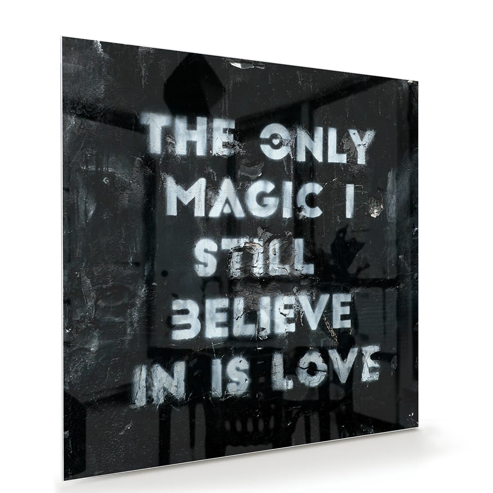 Glazen schilderij met de tekst 'The only magic I still believe in is love', hangt aan de muur in een lichte woonkamer.