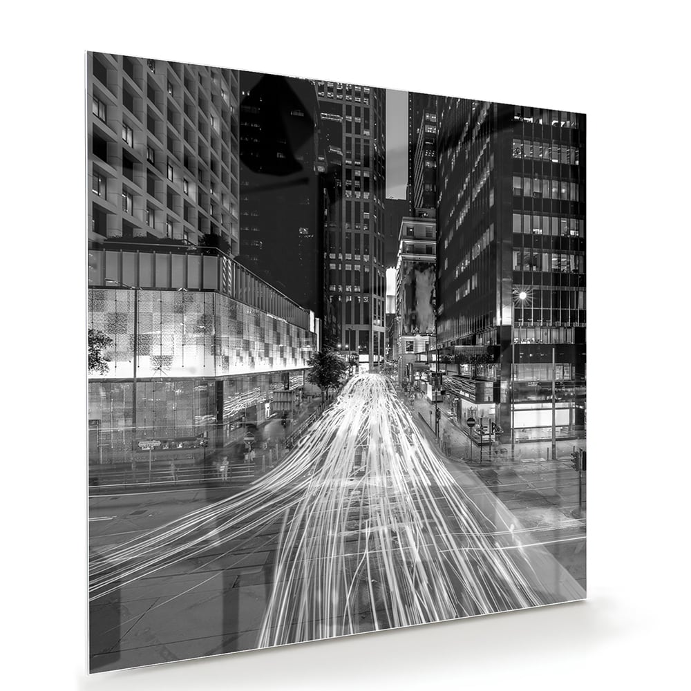 Glazen schilderij met stadslichten in zwart-wit boven een moderne meubelset.