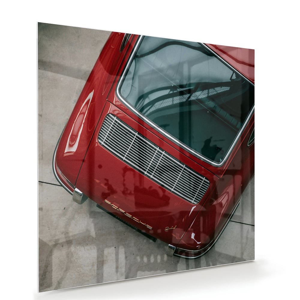 Glazen schilderij van een bovenaf gezien rode auto op een muur.