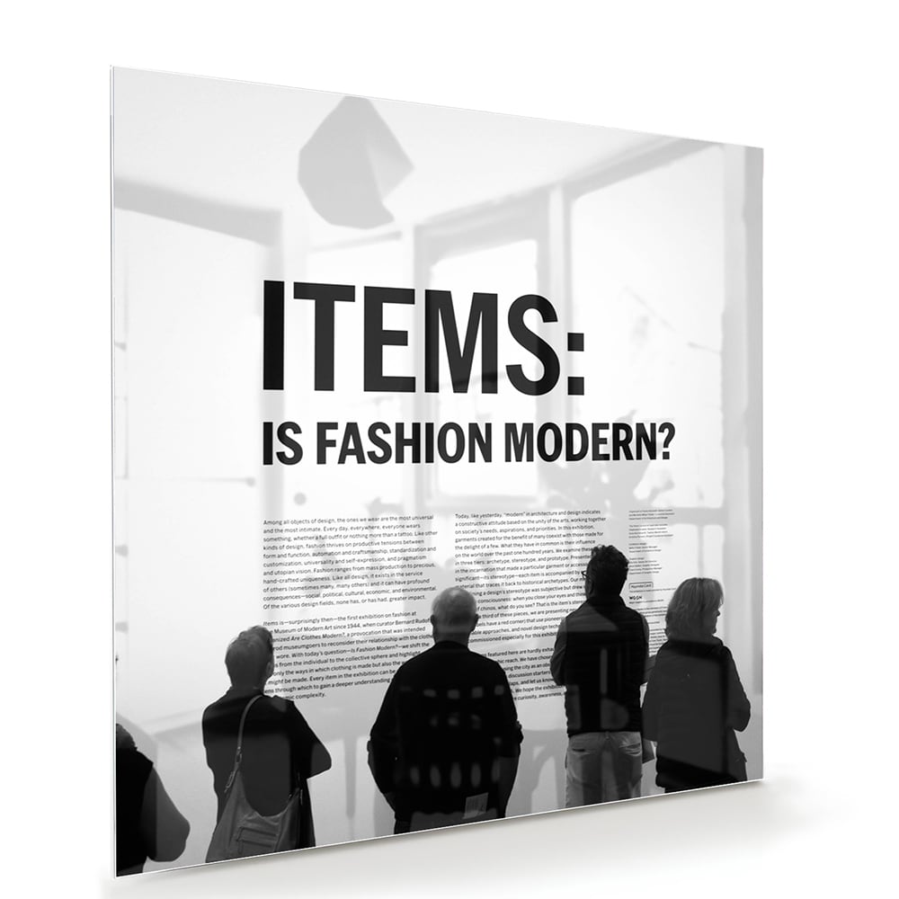 Glazen schilderij met de tekst 'ITEMS: IS FASHION MODERN?', stijlvol gepresenteerd boven een houten meubel.