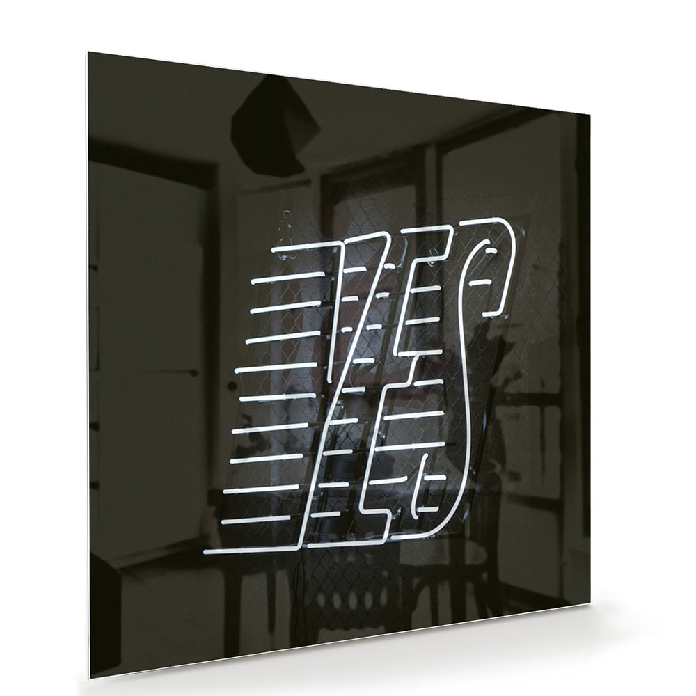 Glazen schilderij met 'YES' text in zwart en wit, hangend aan de muur.
