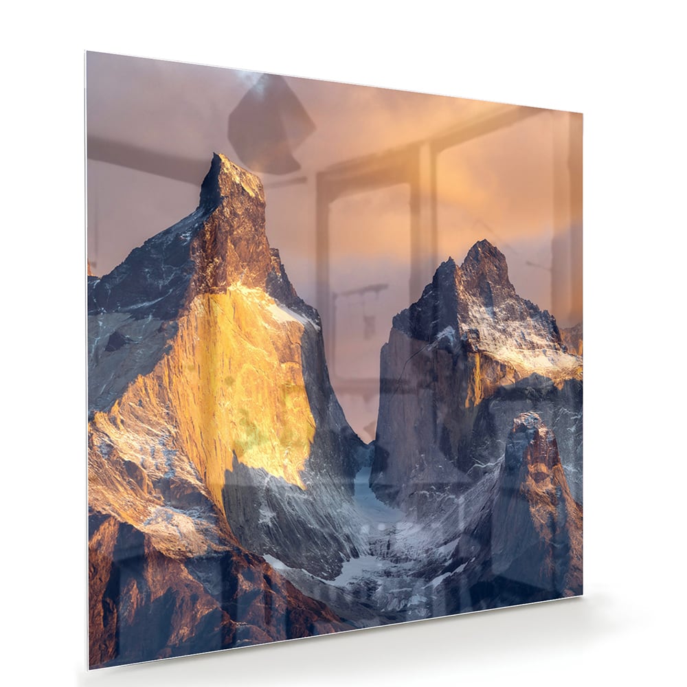 Een glazen schilderij van majestueuze bergen met gouden ochtendlicht