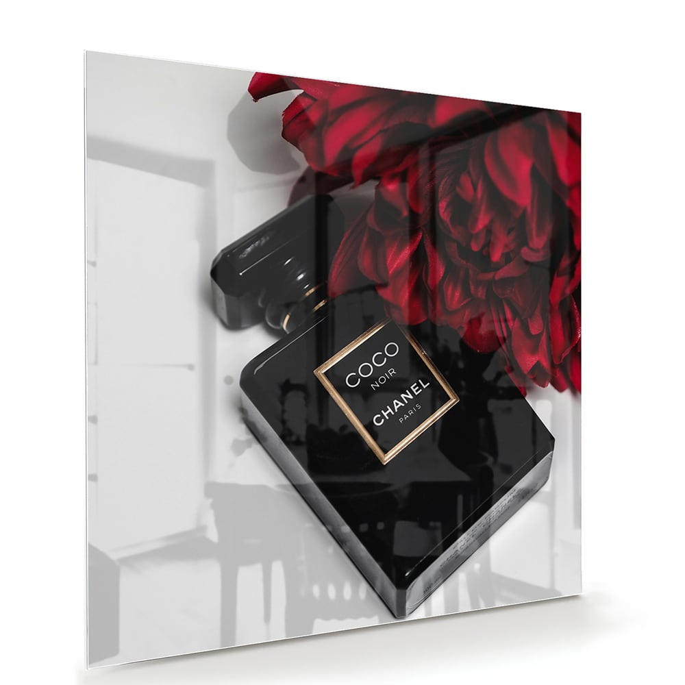 Glazen schilderij van parfumfles met rode bloemen op een witte muur