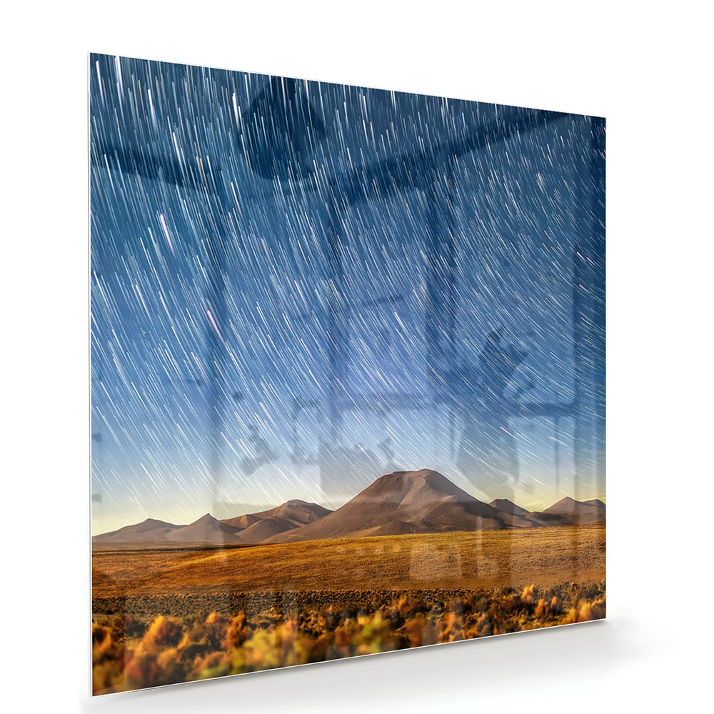 Glazen schilderij met sterrenhemel boven bergen, hangend aan de muur.