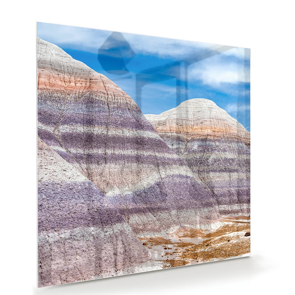 Glazen schilderij van bergen met een blauwe lucht in een moderne woonkamer.