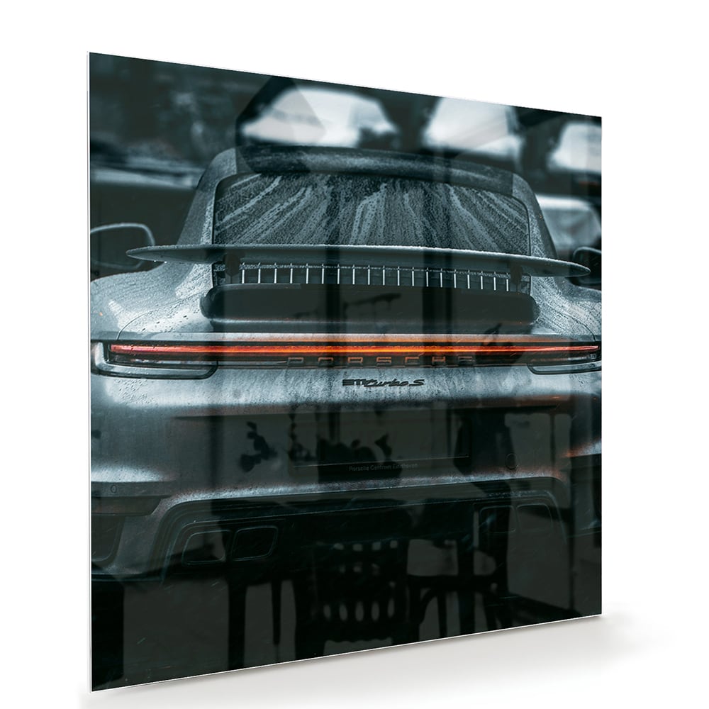 Glazen schilderij van een sportwagen aan de muur in een lichte woonkamer.