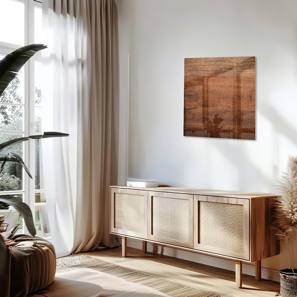Glazen schilderij in warme houttint hangt boven een moderne kast in een woonkamer.