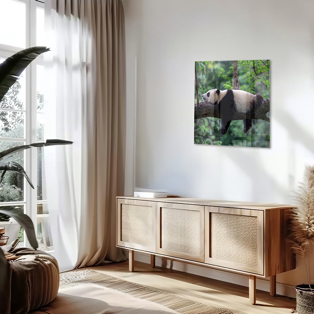 Glazen schilderij van een panda die ontspannen op een tak ligt.