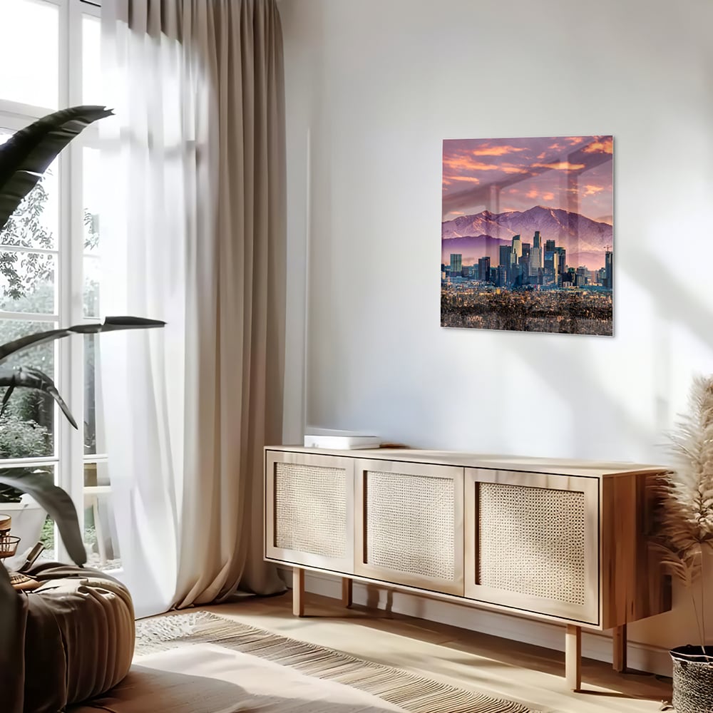 Glazen schilderij van een stadspanorama bij zonsondergang met bergen op de achtergrond.
