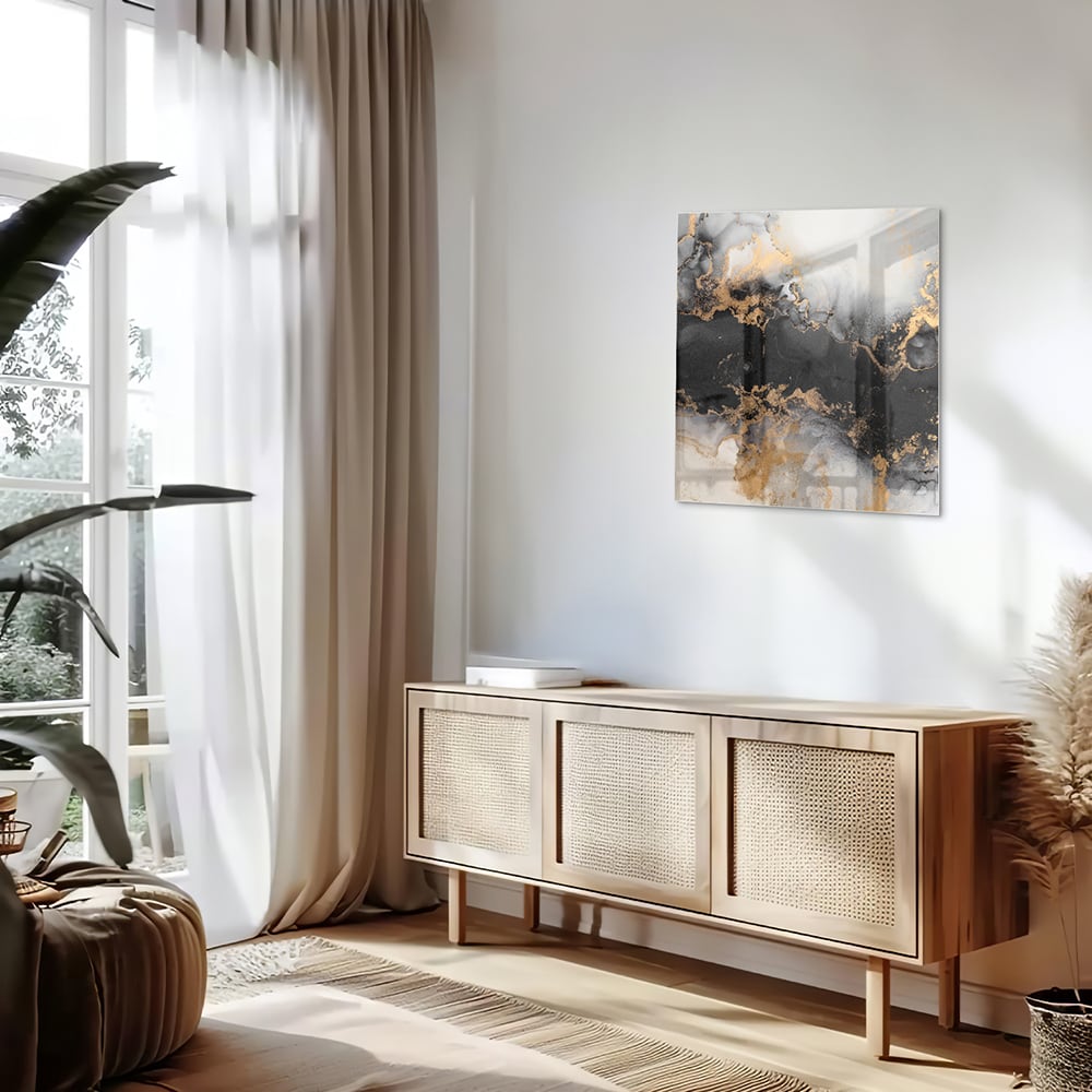 Glazen schilderij met zwarte en gouden abstracte patronen aan de muur boven een houten kast.