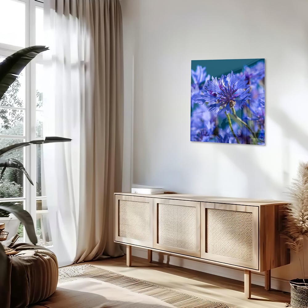 Een glazen schilderij met paarse bloemen op een witte muur, in een sfeervolle woonkamer.