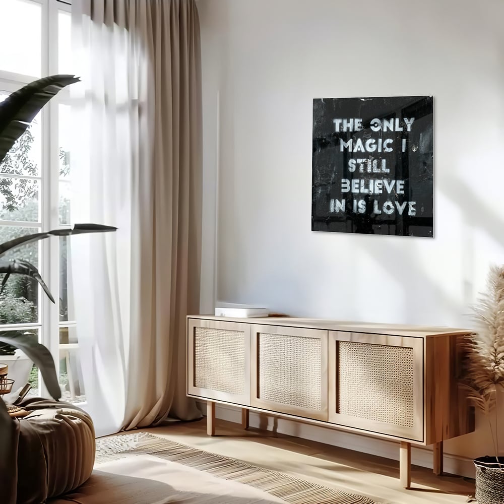 Glazen schilderij met de tekst 'The only magic I still believe in is love', hangt aan de muur in een lichte woonkamer.